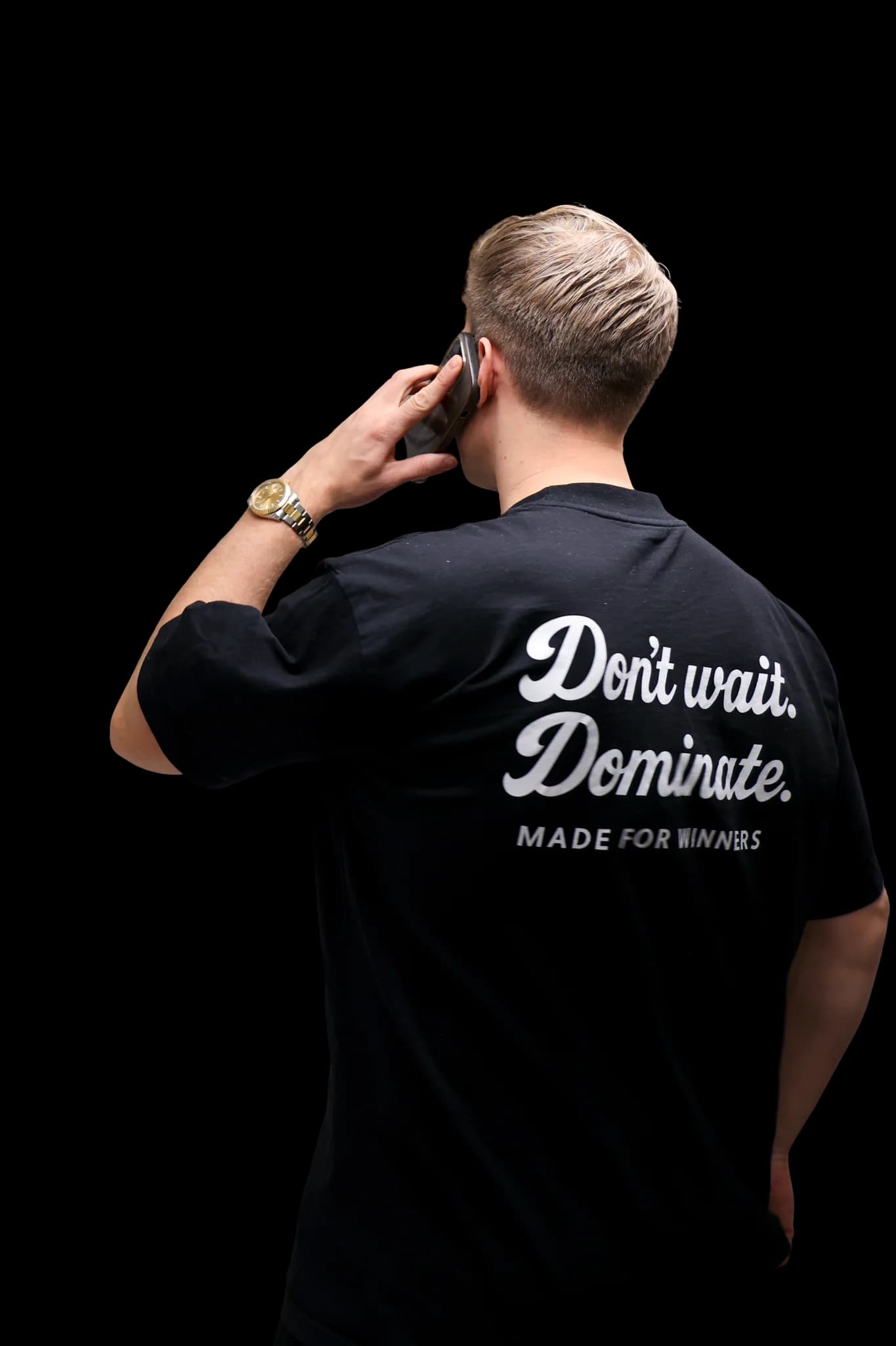 Encoren myyjä puhelimessa Don't wait. Dominate. -paidassa